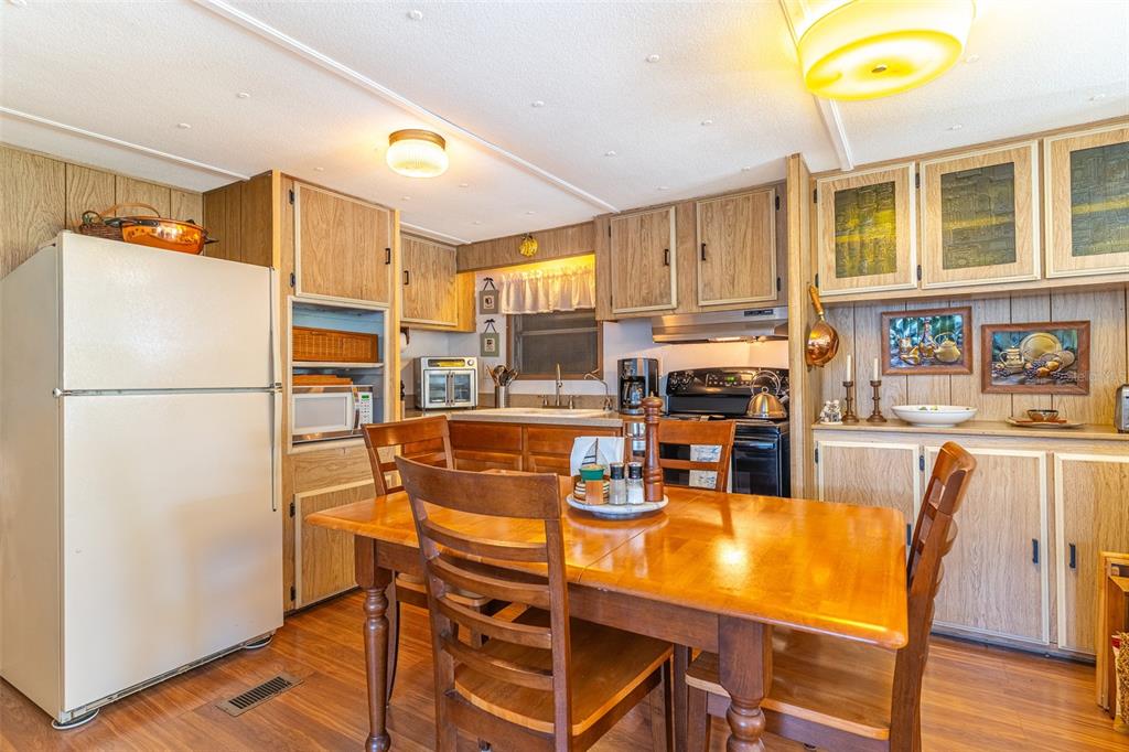 A kitchen features wood-paneled cabinets, a dining table with chairs, and a white refrigerator — 107 EDGEWOOD BOULEVARD, LAKE WALES, FL
