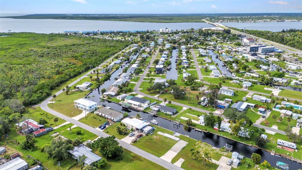 An aerial view shows a residential neighborhood with houses situated along narrow canals and greenery — 14438 STEPHENS ROAD, PORT CHARLOTTE, FL