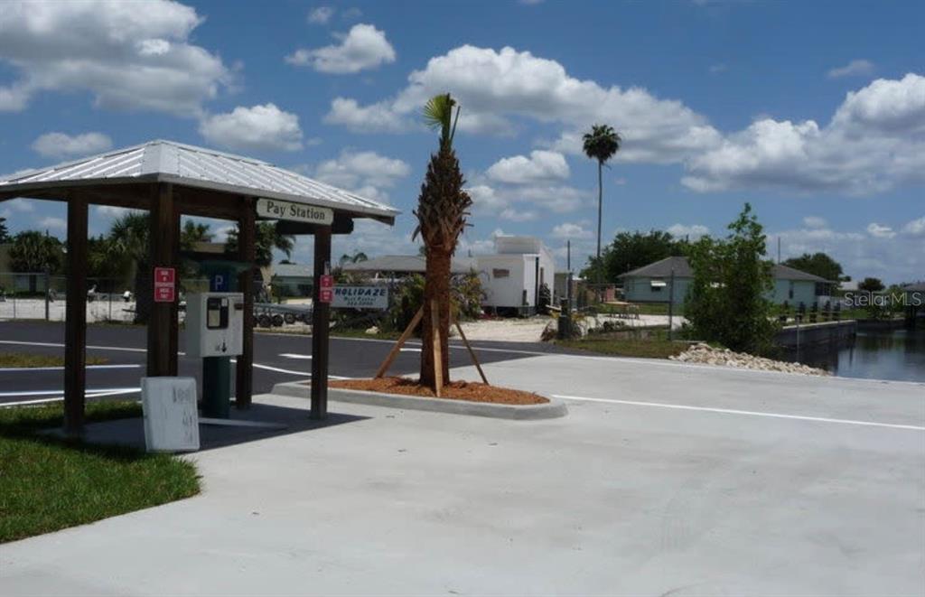 A parking pay station stands under a covered structure next to a palm tree — 14438 STEPHENS ROAD, PORT CHARLOTTE, FL
