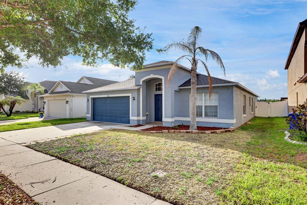 A blue single-story house with a two-car garage and a palm tree in the yard — 8105 TAR HOLLOW DRIVE, GIBSONTON, FL