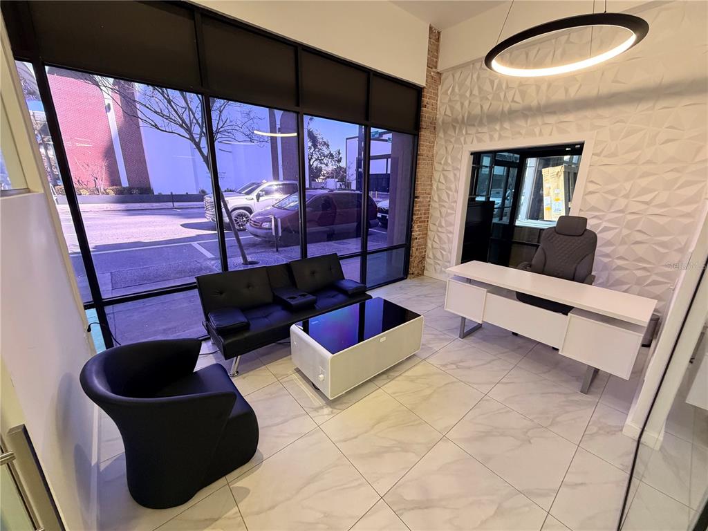 A modern office space features a desk, seating area, large windows, and textured wall panels — 1006 N FLORIDA AVENUE, TAMPA, FL