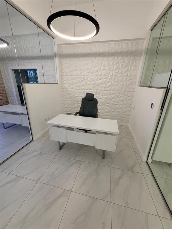 A modern office features a white desk, a black chair, and a textured accent wall — 1006 N FLORIDA AVENUE, TAMPA, FL