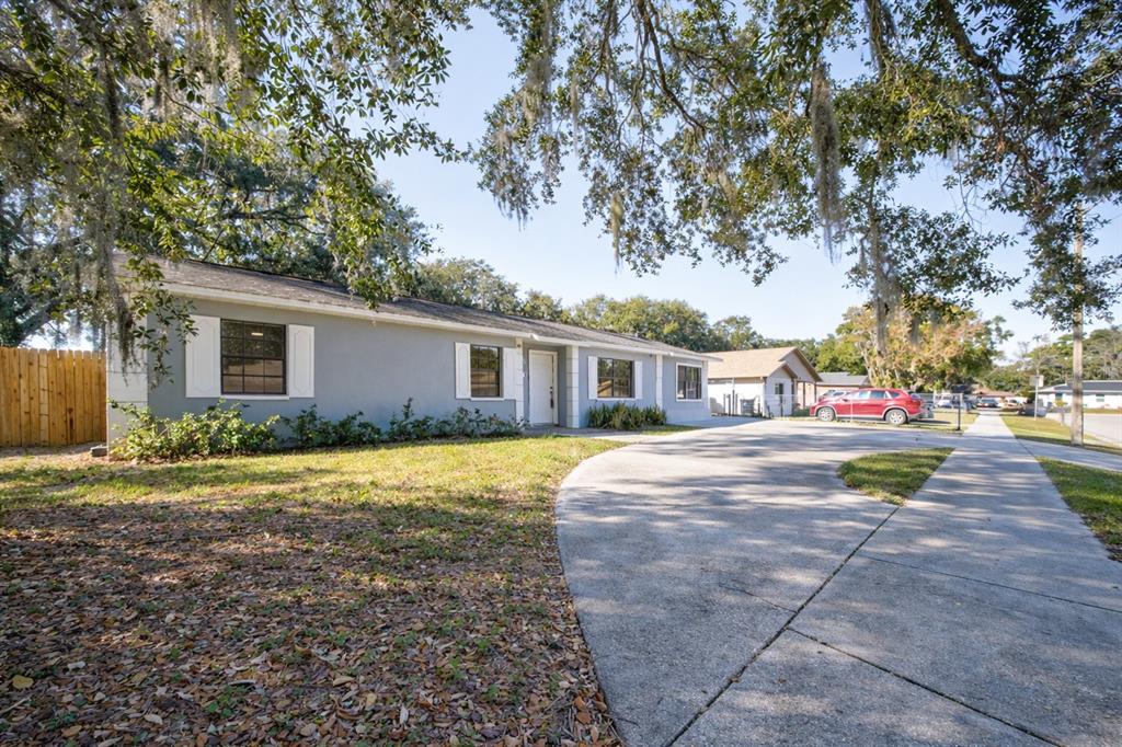 A single-story gray house with white shutters and a concrete driveway under large oak trees — 720 SWISS DRIVE, LAKELAND, FL