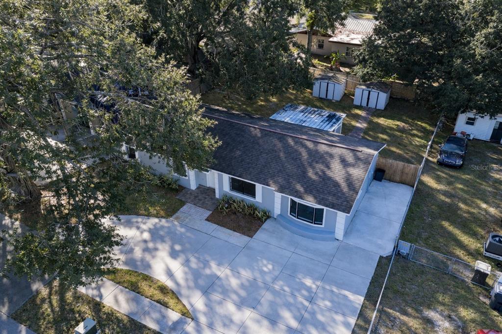 An aerial view shows a single-story house with a gray roof, driveway, and backyard sheds — 720 SWISS DRIVE, LAKELAND, FL
