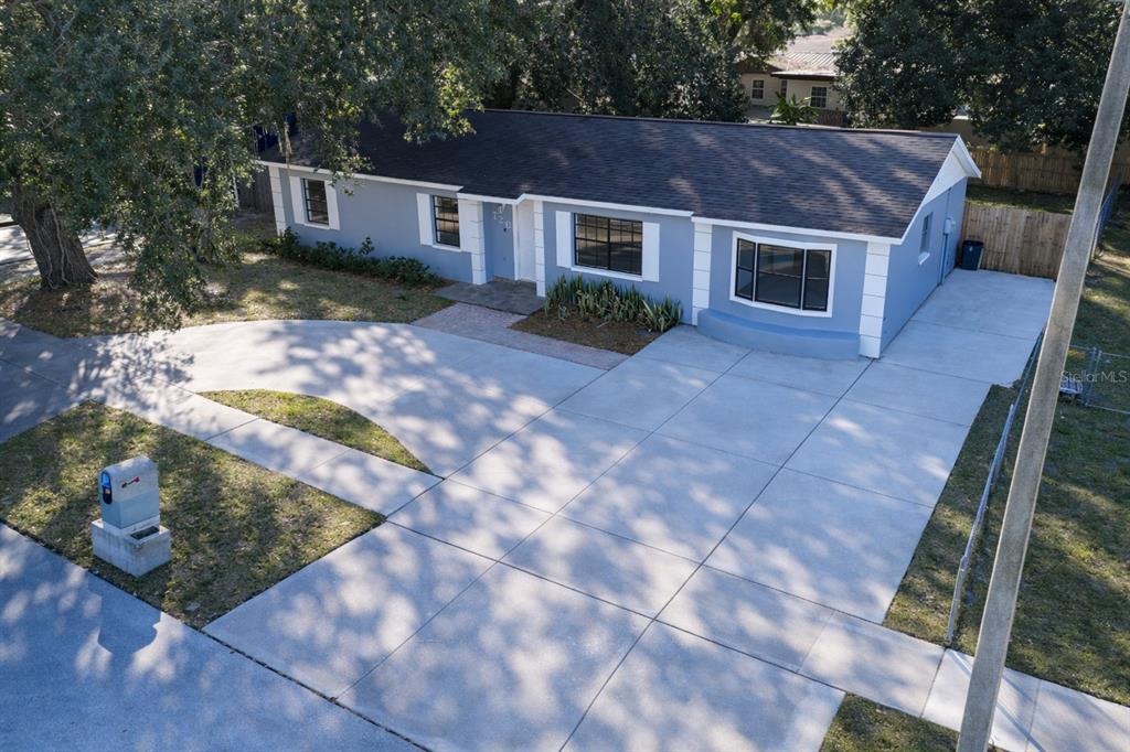 An aerial view shows a blue single-story house with a large concrete driveway and lawn — 720 SWISS DRIVE, LAKELAND, FL