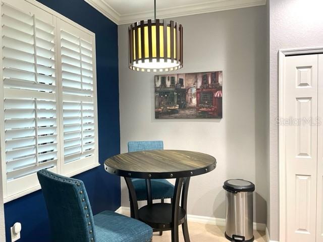 A dining nook features a round wooden table, blue chairs, and a modern pendant light — 7019 RIVER HAMMOCK DRIVE UNIT 404, BRADENTON, FL