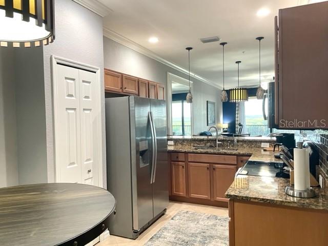 A kitchen features wood cabinets, stainless steel appliances, granite countertops, and pendant lighting — 7019 RIVER HAMMOCK DRIVE UNIT 404, BRADENTON, FL