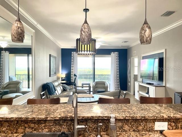 A kitchen counter overlooks a living room with a sofa, armchairs, and a balcony view — 7019 RIVER HAMMOCK DRIVE UNIT 404, BRADENTON, FL