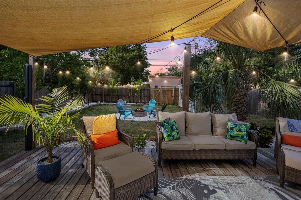 A wooden deck with outdoor furniture and a fire pit area under a shade sail — 1018 55TH AVENUE N, ST PETERSBURG, FL