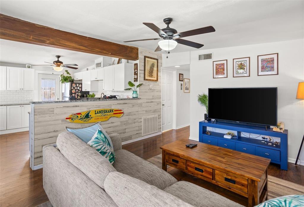 A living room with a grey sofa, wooden coffee table, and blue media console — 1018 55TH AVENUE N, ST PETERSBURG, FL