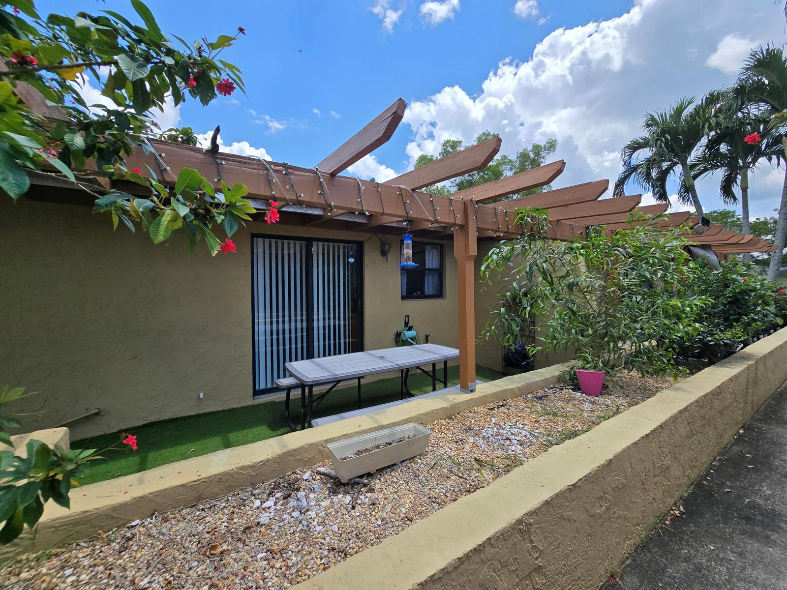 A patio area features a wooden pergola, a picnic table, and a raised gravel planter — 1155 White Pine Pine # 1155, Wellington FL 33414, WELLINGTON, FL