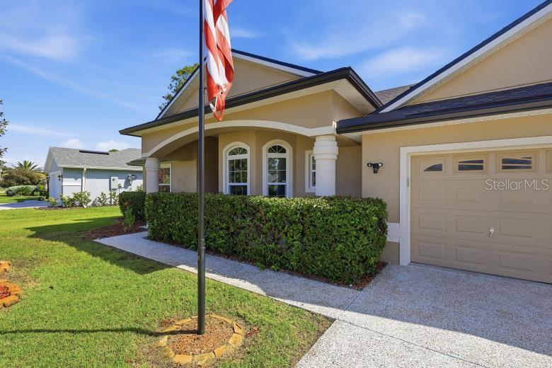 A beige house exterior features a front porch, a flag pole, and a garage — 69 WELLESLEY LANE, PALM COAST, FL, FL