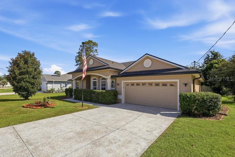 A single-story house with a beige exterior, a two-car garage, and a front lawn — 69 WELLESLEY LANE, PALM COAST, FL, FL