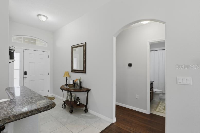 An entryway with tile flooring, a console table, and an arched doorway leading to a bathroom — 69 WELLESLEY LANE, PALM COAST, FL, FL