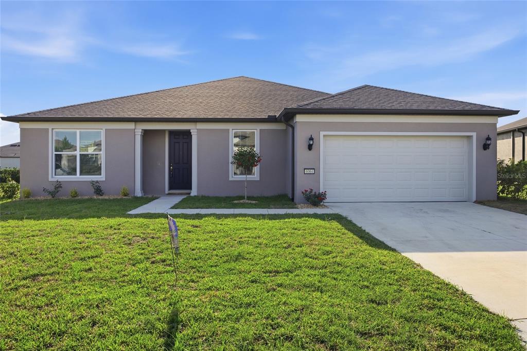 A single-story house with a gray stucco exterior, a two-car garage, and a front lawn — 6064 SW 86TH TERRACE ROAD, OCALA, FL