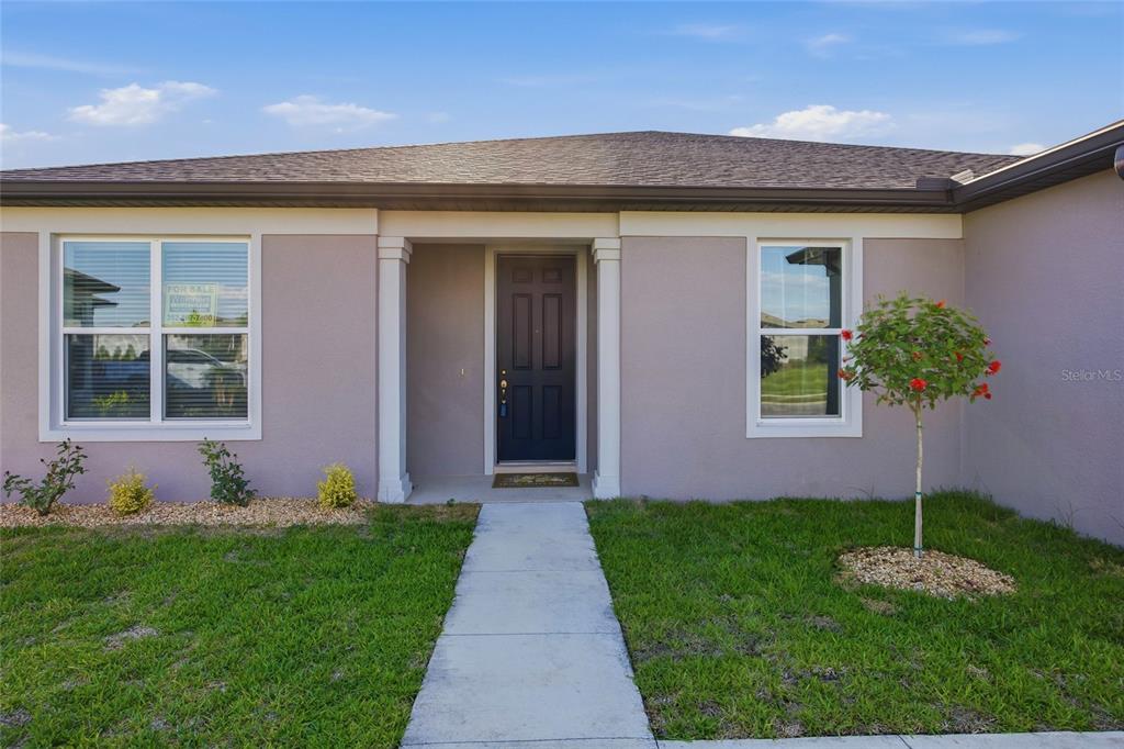 The exterior of a single-story house features a dark front door and a concrete walkway — 6064 SW 86TH TERRACE ROAD, OCALA, FL