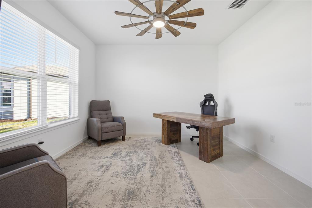 A home office with a wooden desk, two armchairs, a rug, and a ceiling fan — 6064 SW 86TH TERRACE ROAD, OCALA, FL