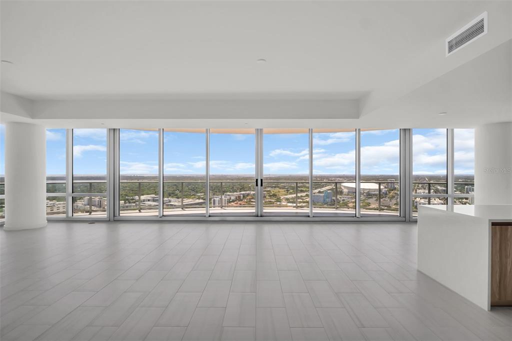 An open-concept living area features light tile flooring, white walls, and floor-to-ceiling windows — 400 CENTRAL AVENUE UNIT 3401, ST PETERSBURG, FL
