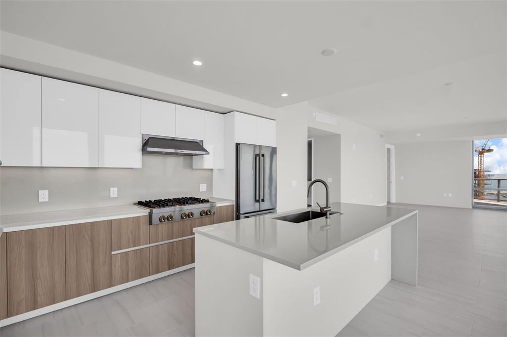 A modern kitchen features white upper cabinets, wood-tone lower cabinets, and a gray island countertop — 400 CENTRAL AVENUE UNIT 3401, ST PETERSBURG, FL