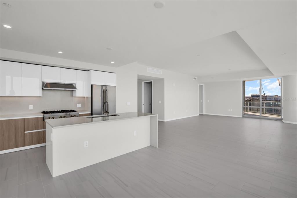A modern kitchen with white cabinets and a center island opens into a spacious living area — 400 CENTRAL AVENUE UNIT 3401, ST PETERSBURG, FL