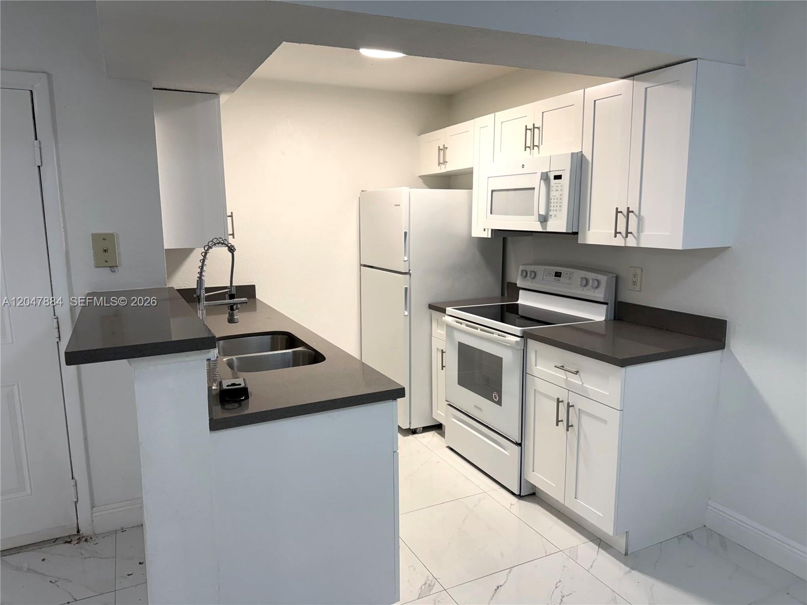 A kitchen features white cabinets, dark countertops, a white refrigerator, and a white stove — 15560 SW 104th Ter # 619, Miami FL 33196, MIAMI, FL