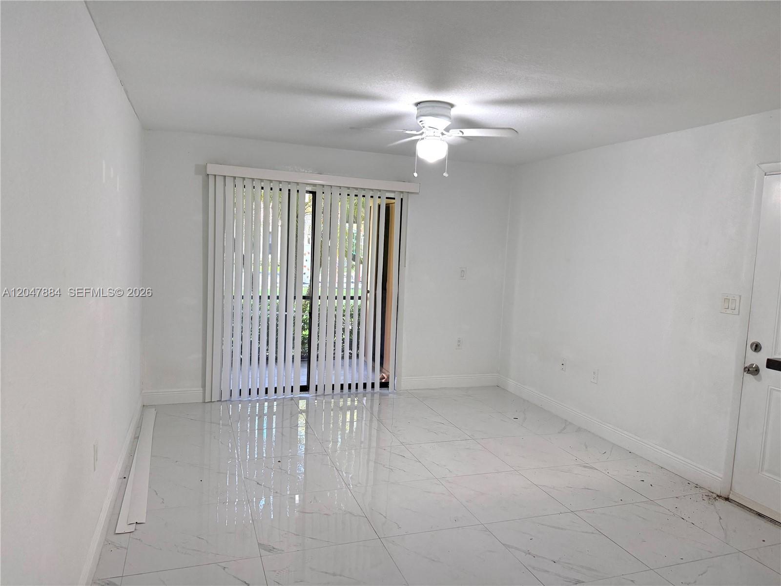 A bright room features white walls, white tile flooring, a ceiling fan, and vertical blinds — 15560 SW 104th Ter # 619, Miami FL 33196, MIAMI, FL