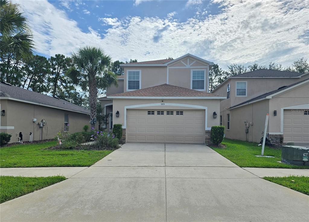 A two-story suburban house with a beige stucco exterior and a two-car garage — 7855 TUSCANY WOODS DRIVE, TAMPA, FL