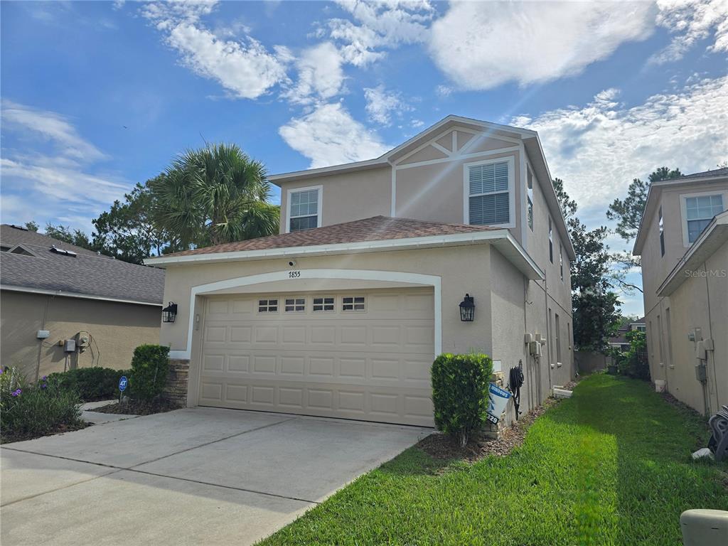 A two-story suburban house with a beige stucco exterior and a two-car garage — 7855 TUSCANY WOODS DRIVE, TAMPA, FL