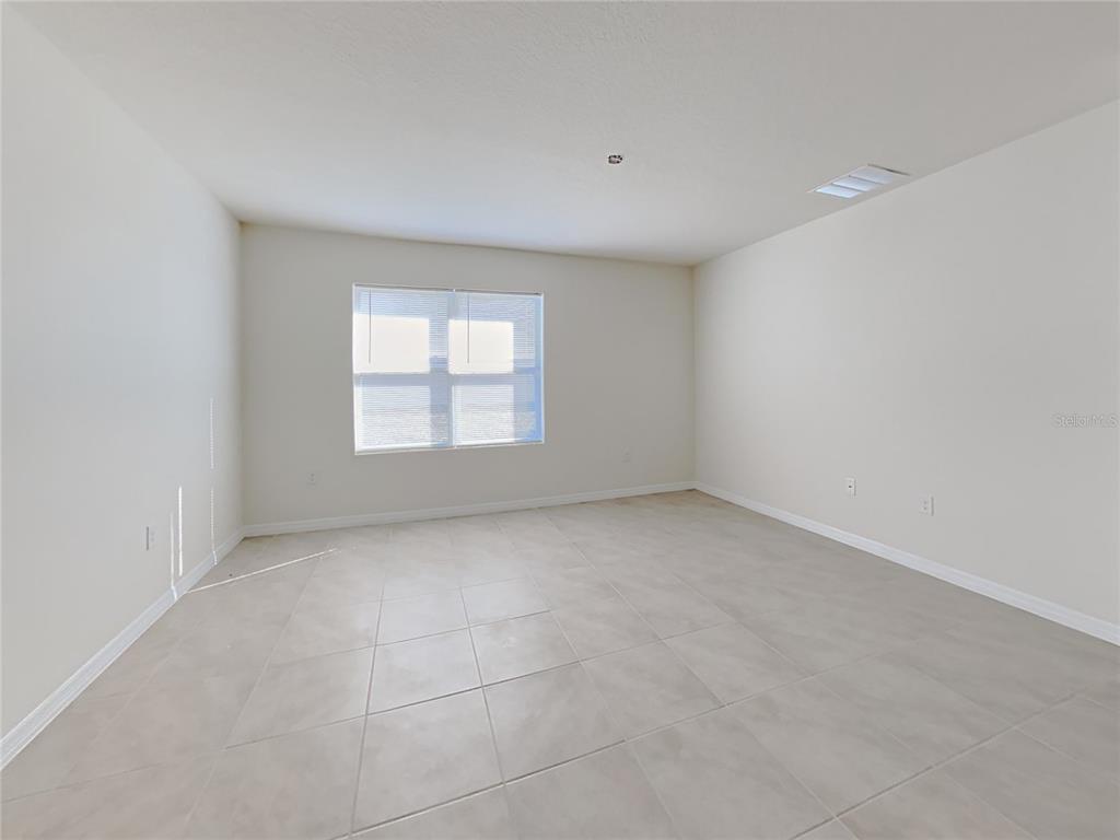 An empty room with light-colored tile flooring, white walls, and a single window — 9678 BLACK WALNUT DRIVE, CLERMONT, FL