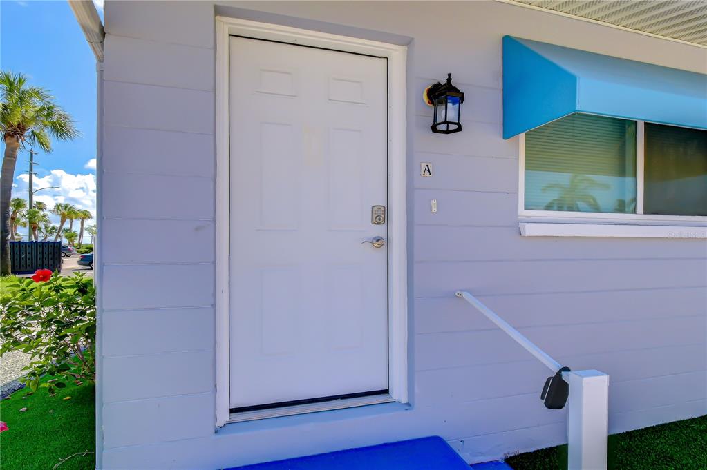 A white front door with a letter A sign is on a light blue building — 190 73RD AVENUE UNIT A, ST PETE BEACH, FL