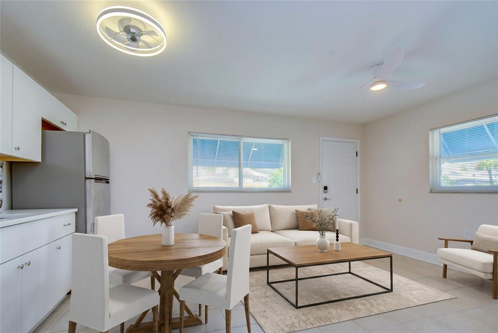 An open-concept living and dining area features white cabinetry, a round table, and neutral furniture — 190 73RD AVENUE UNIT A, ST PETE BEACH, FL
