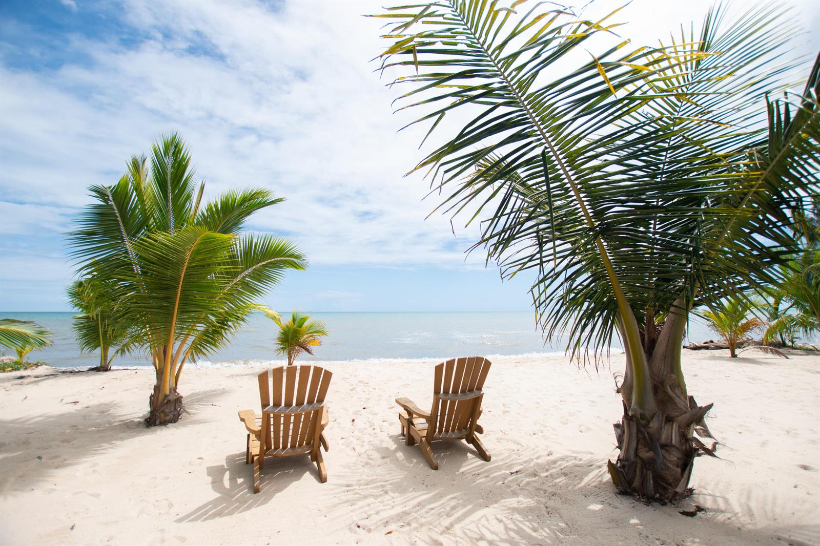 Two wooden chairs sit on a sandy beach overlooking the ocean under a blue sky — 0 Mile 15, Lot 1180 Placencia Road, FL
