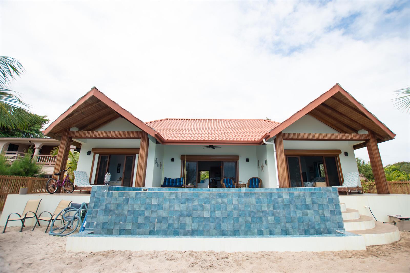 An open-concept living and dining area features vaulted wood ceilings and sliding doors to a beach — 0 Mile 15, Lot 1180 Placencia Road, FL