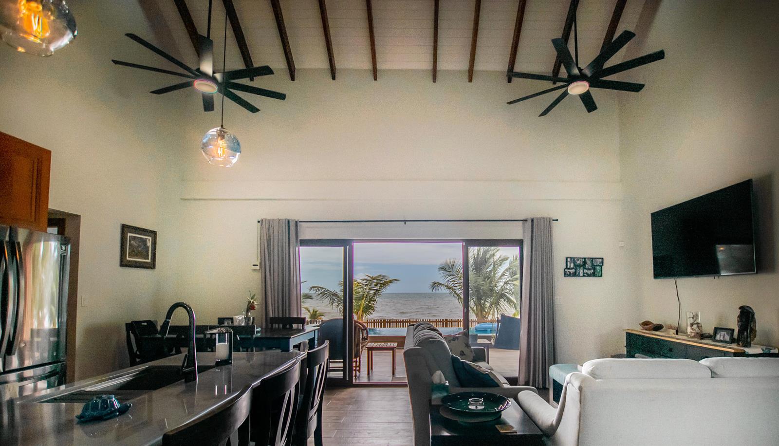 A covered patio with a hanging sofa, wicker chairs, and a pool overlooks tropical greenery — 0 Mile 15, Lot 1180 Placencia Road, FL