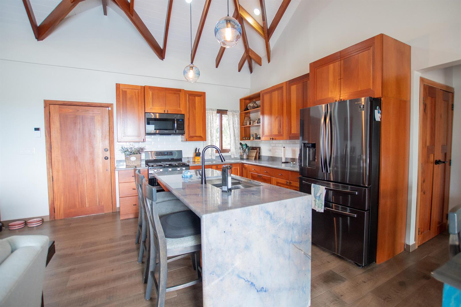 A kitchen with wood cabinets and a large island opens into a living area — 0 Mile 15, Lot 1180 Placencia Road, FL
