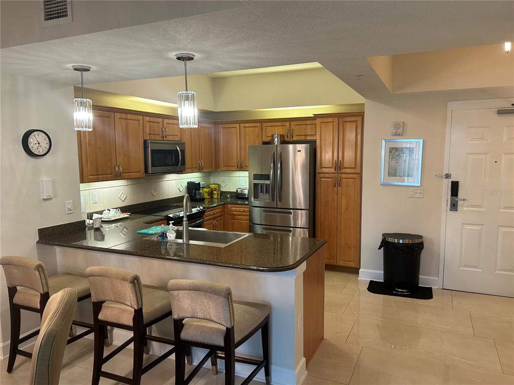 A kitchen features wood cabinets, granite countertops, stainless steel appliances, and a breakfast bar — 200 OCEAN CREST DRIVE UNIT 118, PALM COAST, FL