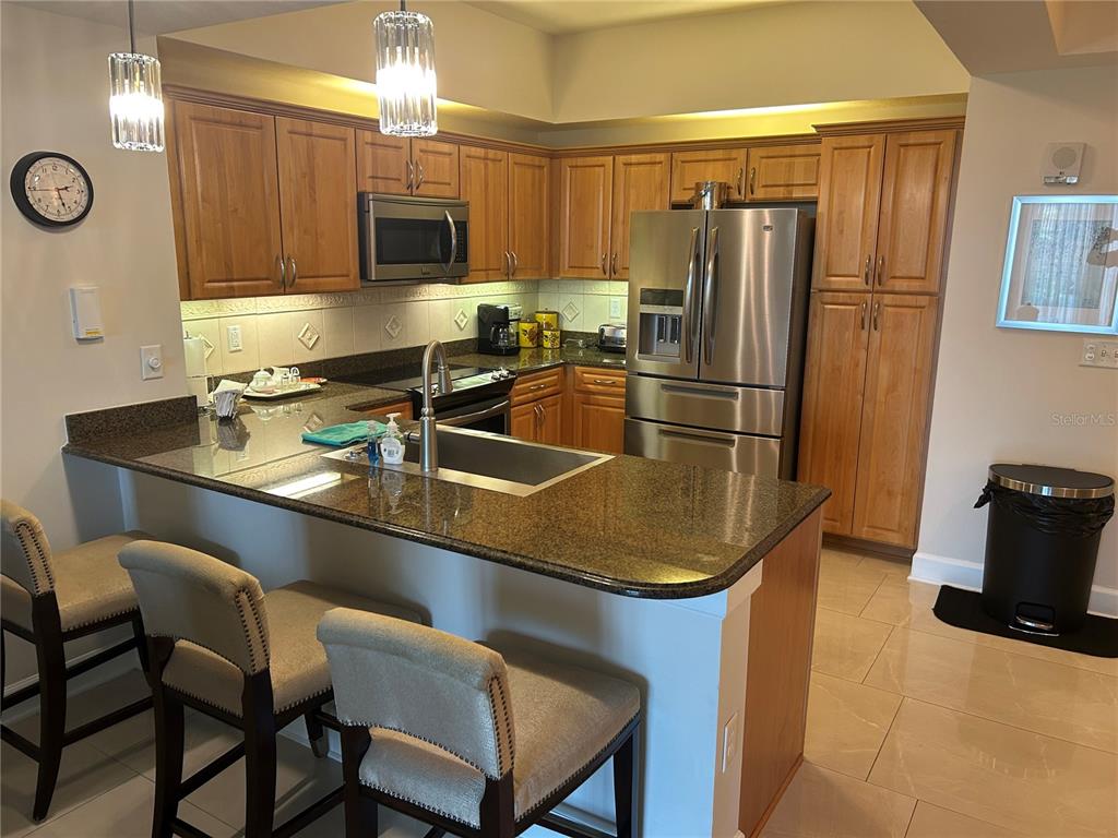A kitchen features wood cabinets, granite countertops, stainless steel appliances, and a breakfast bar — 200 OCEAN CREST DRIVE UNIT 118, PALM COAST, FL