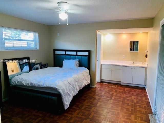A bedroom with a dark wood bed frame, parquet flooring, and an attached vanity area — 6720 NW 28th St, Sunrise FL 33313, SUNRISE, FL