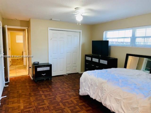 A bedroom with parquet flooring, a white closet, a dresser with a television, and a bed — 6720 NW 28th St, Sunrise FL 33313, SUNRISE, FL