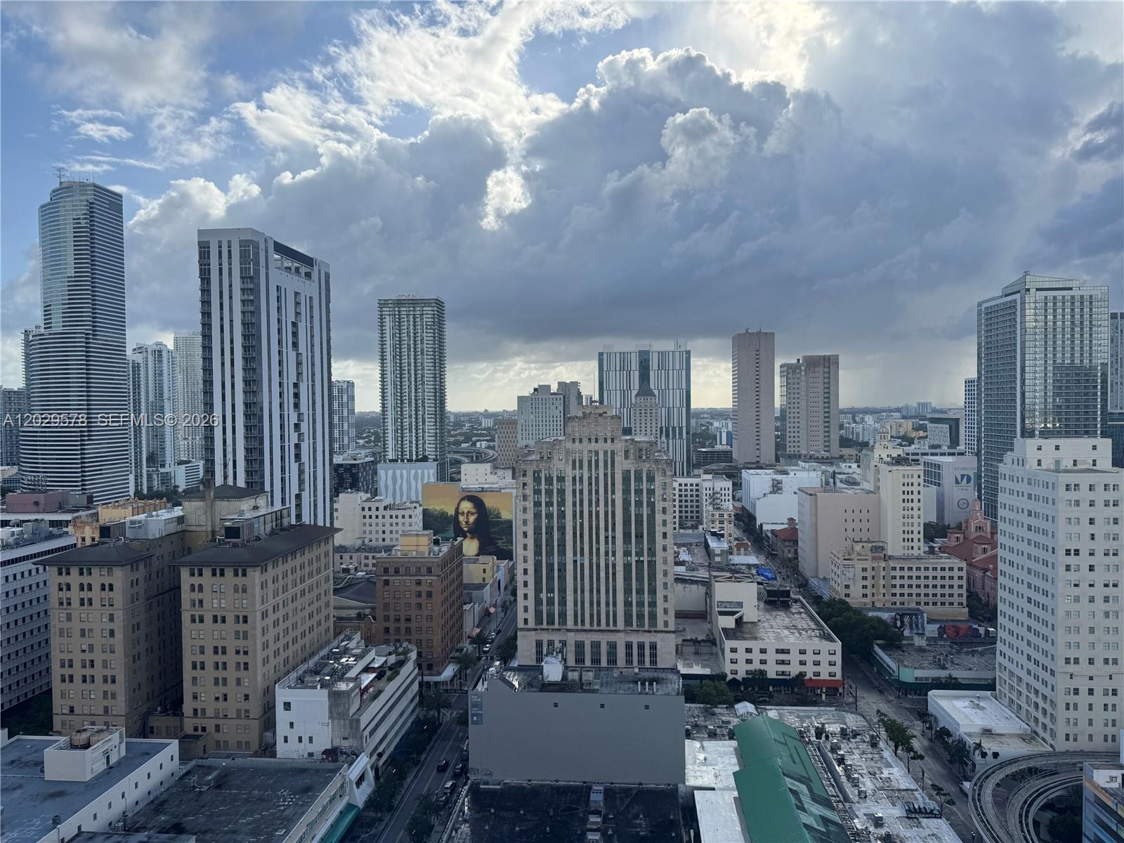 An elevated view of a dense city skyline featuring numerous high-rise buildings under cloudy skies — 50 Biscayne Blvd # 2707, Miami FL 33132, MIAMI, FL