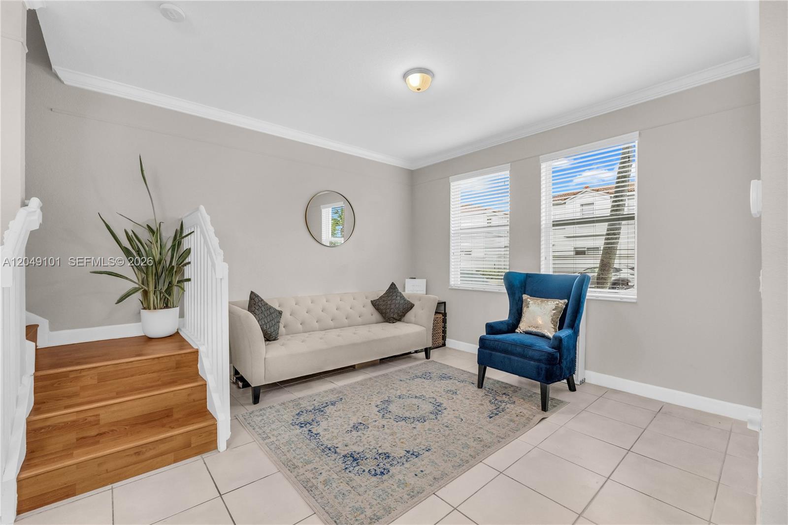 A living room features a beige tufted sofa, blue armchair, area rug, and wooden stairs — 4015 SW 156th Ave # 210, Miramar FL 33027, MIRAMAR, FL