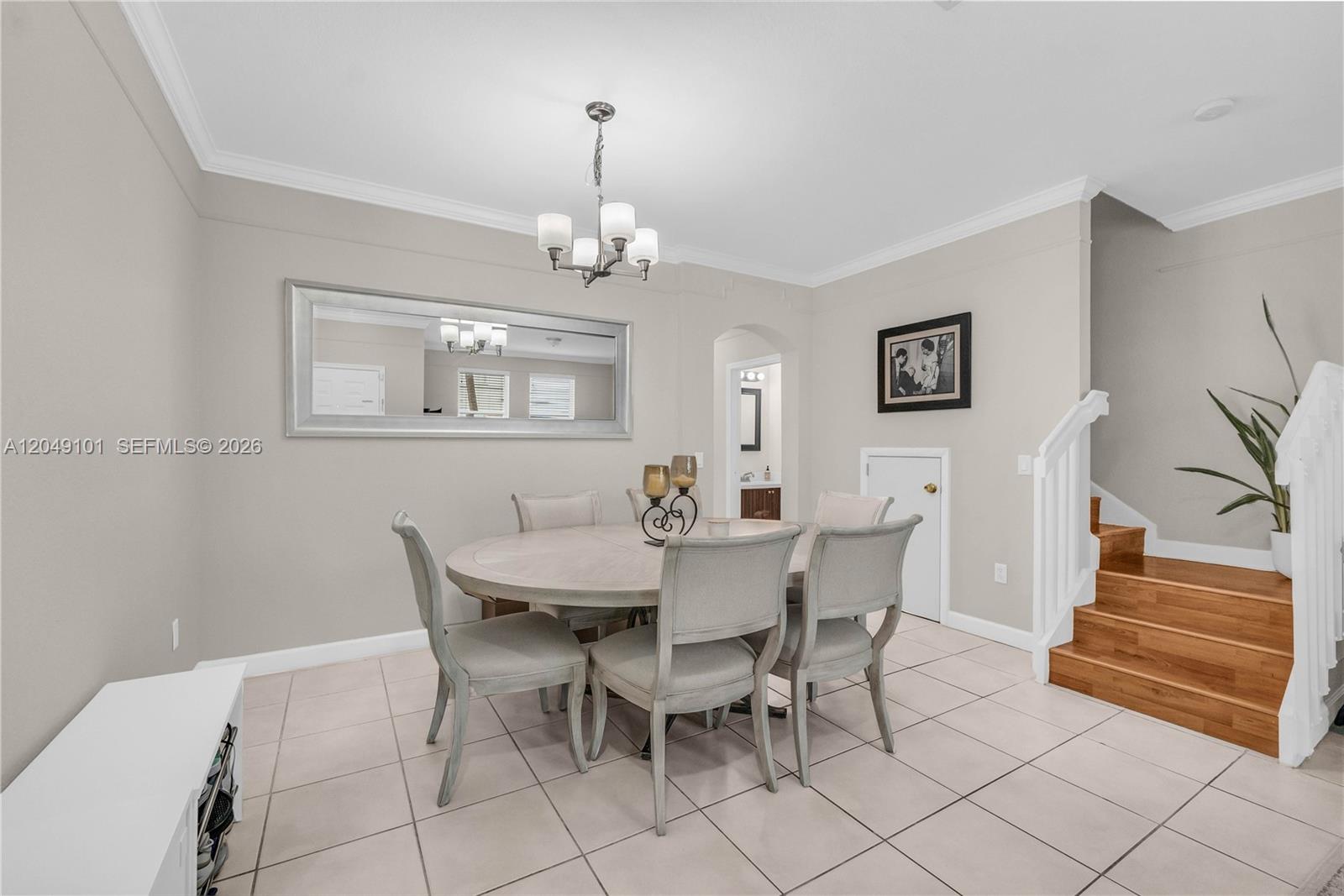 A dining room features a round table, upholstered chairs, a large mirror, and wooden stairs — 4015 SW 156th Ave # 210, Miramar FL 33027, MIRAMAR, FL