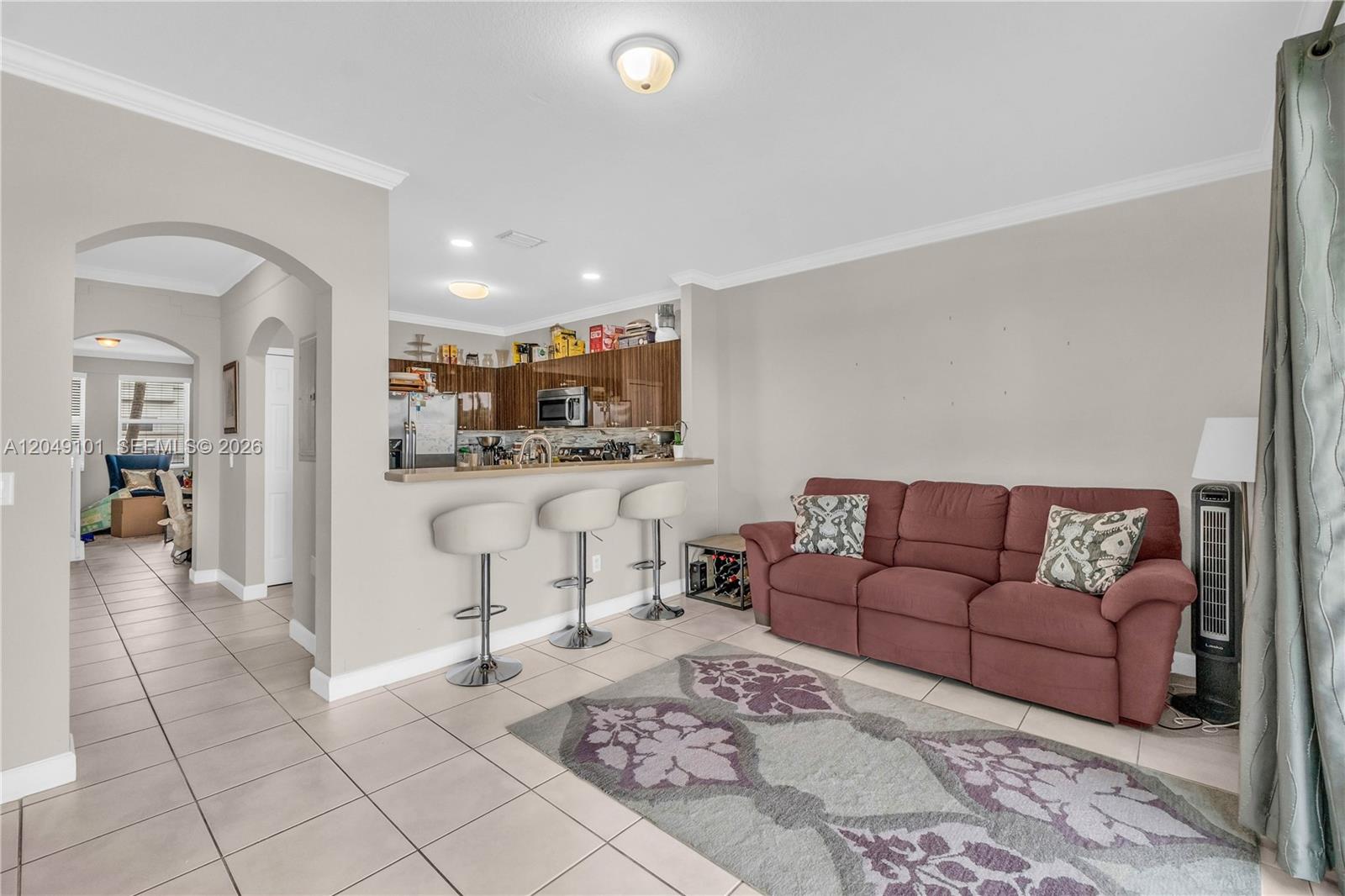 A living room with tile floors features a sofa, a rug, and a kitchen breakfast bar — 4015 SW 156th Ave # 210, Miramar FL 33027, MIRAMAR, FL