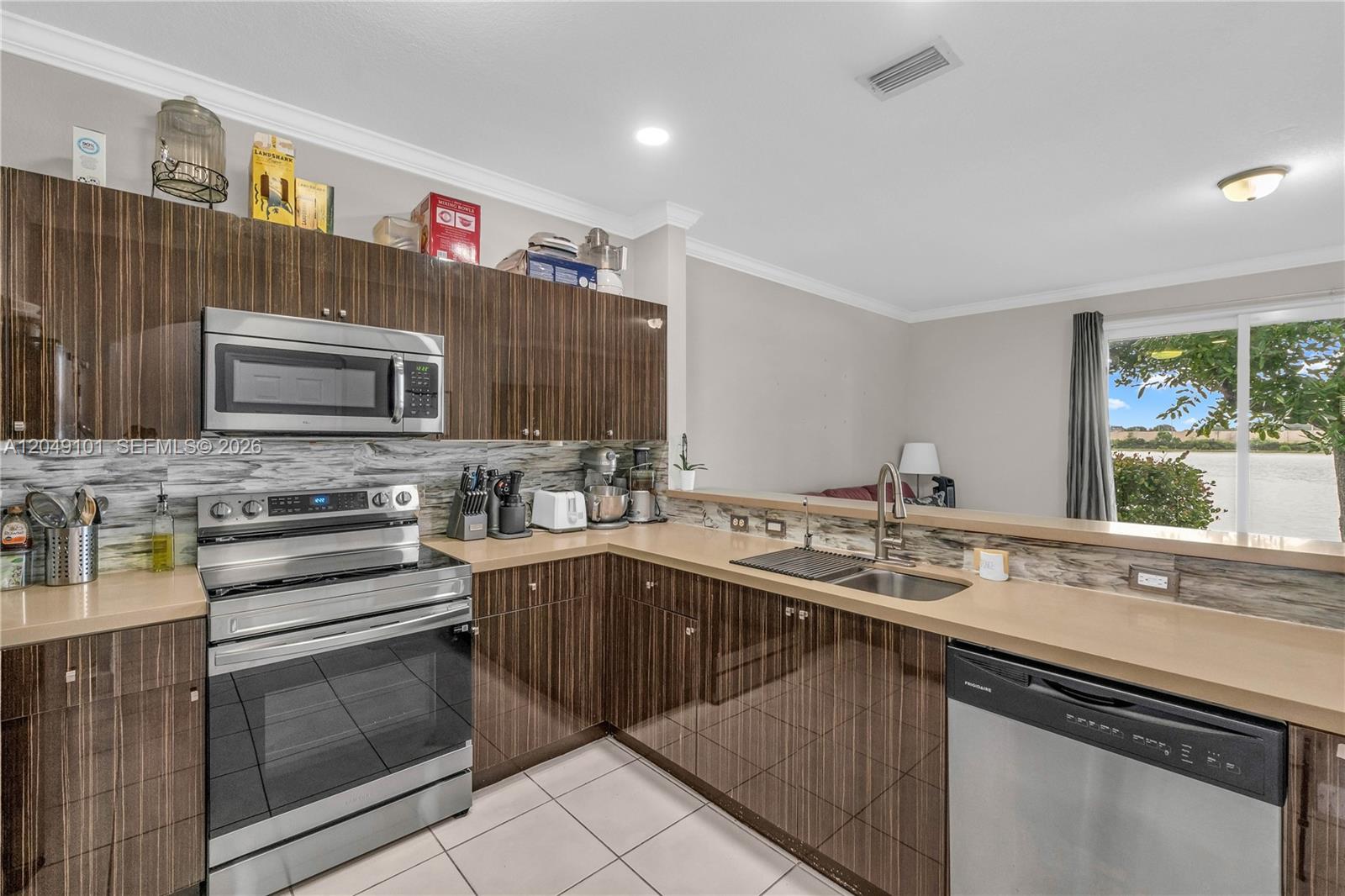 A kitchen features dark wood-grain cabinets, stainless steel appliances, and a view of a lake — 4015 SW 156th Ave # 210, Miramar FL 33027, MIRAMAR, FL