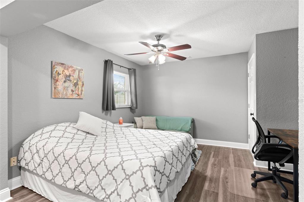 A bedroom with gray walls, wood-look flooring, a ceiling fan, and a bed with patterned bedding — 1019 SUSAN DRIVE, LAKELAND, FL