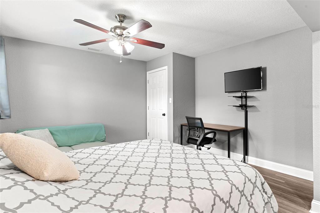 A bedroom features a bed, a desk with a chair, a television, and a ceiling fan — 1019 SUSAN DRIVE, LAKELAND, FL