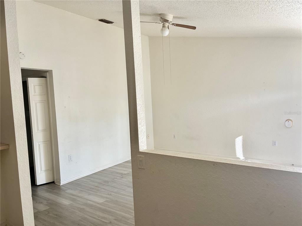An interior view shows a living area with light-colored flooring, a ceiling fan, and walls — 4092 JASON ROAD, SPRING HILL, FL