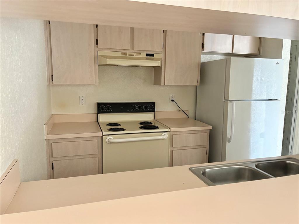 A kitchen features light-colored cabinets, a white stove, a refrigerator, and a double sink — 4092 JASON ROAD, SPRING HILL, FL