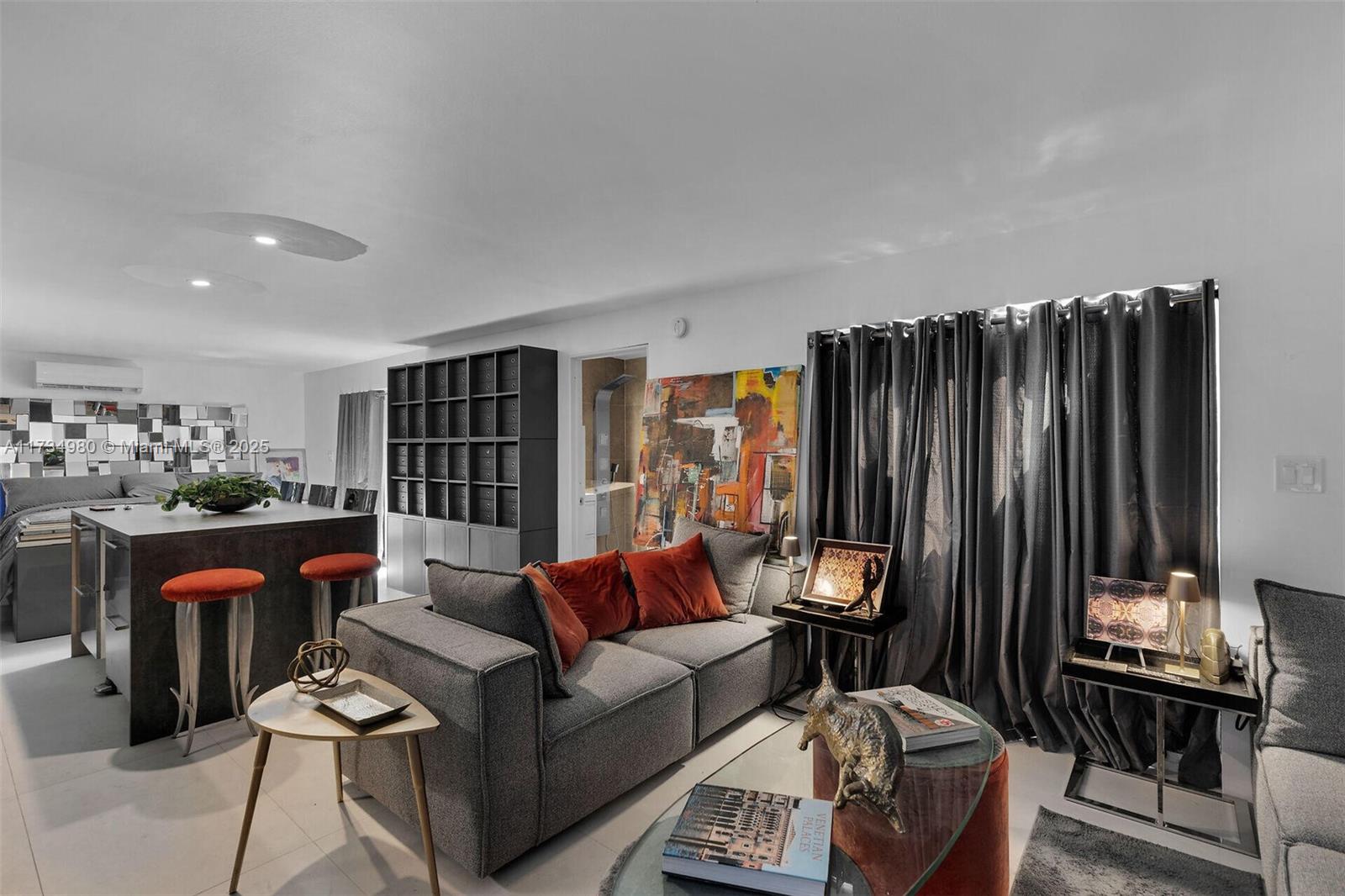 A modern living room features a grey sofa, kitchen island with bar stools, and dark curtains — 98703 Overseas Hwy, Key Largo FL 33037, KEY LARGO, FL