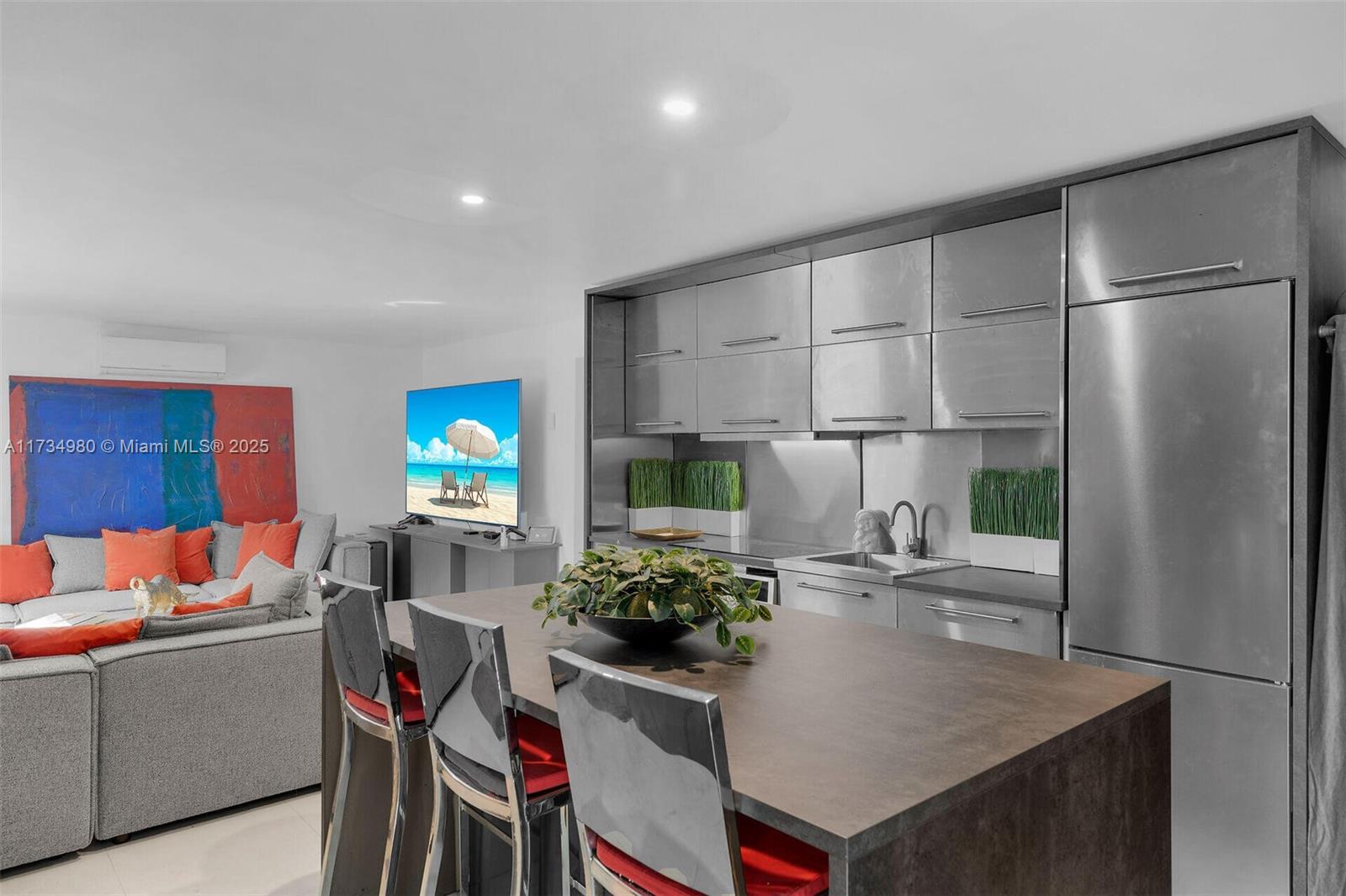 A modern kitchen features stainless steel cabinetry and a dark island with bar seating — 98703 Overseas Hwy, Key Largo FL 33037, KEY LARGO, FL